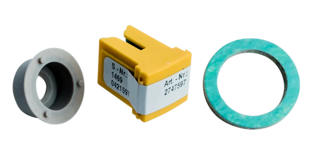 Drei Komponenten eines Umrüstsets für Heizungen, einschließlich einer grauen Dichtung, einem gelben Bauteil und einem blauen Ring, von der Marke Wolf.